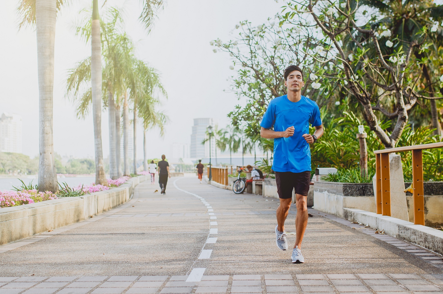 man on a jogging path near a beach at the edge of a coastal city